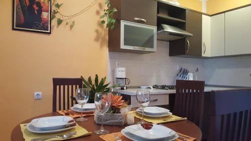 a kitchen with a table with plates and wine glasses at Apartman Ema 4+2 in Koromačno