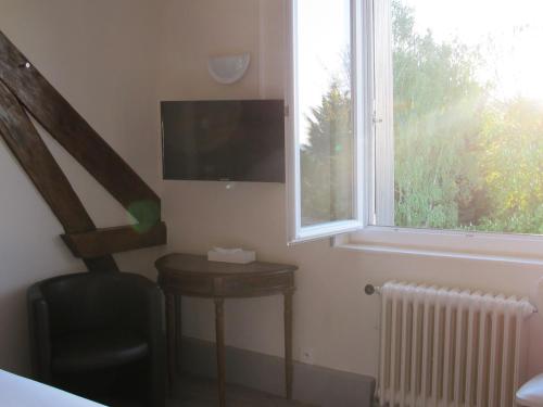 a room with a television and a table and a window at Logis Deshors-Foujanet in Chamboulive