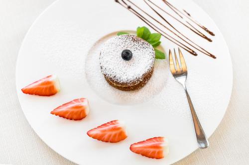 a white plate with a dessert with strawberries on it at Bukowy Park Hotel Medical SPA in Polanica-Zdrój