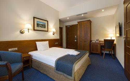 a hotel room with a bed and a desk at Bukowy Park Hotel Medical SPA in Polanica-Zdrój
