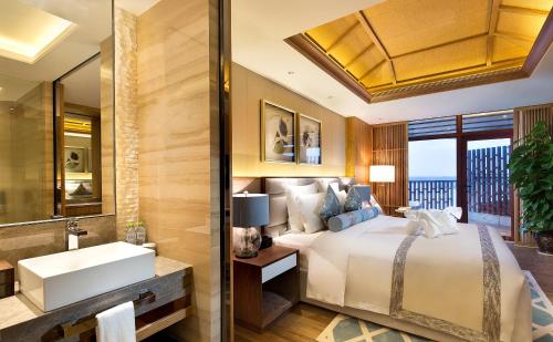 a bedroom with a bed and a sink and a mirror at Wyndham Grand Plaza Royale Wenchang in Wenchang
