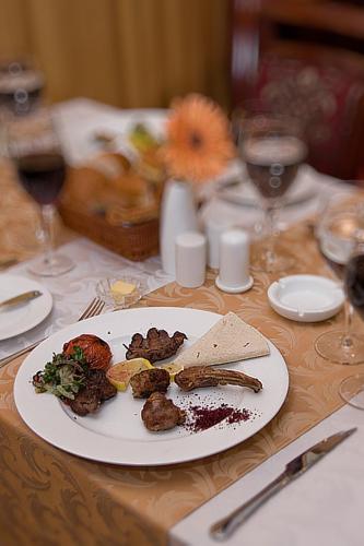 a white plate of food on a table with wine glasses at Golden Coast Hotel in Baku