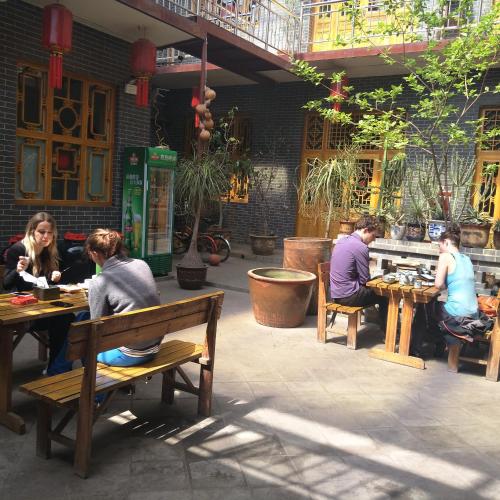 a group of people sitting at tables in a patio at Pingyao Jiaxin Guesthouse in Pingyao