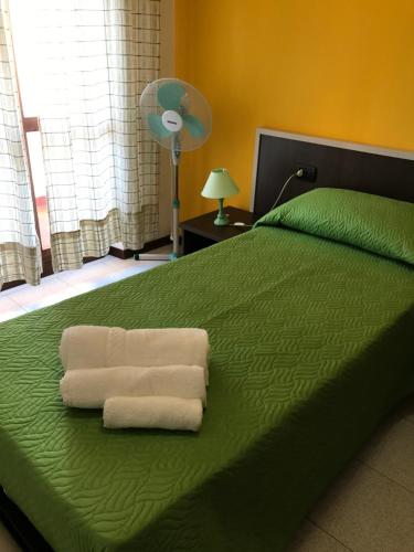 a bedroom with a green bed with towels on it at Hotel Marina in Badesi
