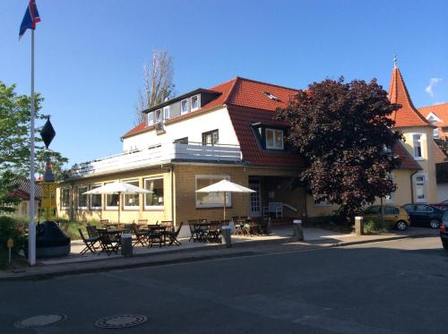 a building with tables and umbrellas on a street at Hotel Seeburg in Sankt Peter-Ording