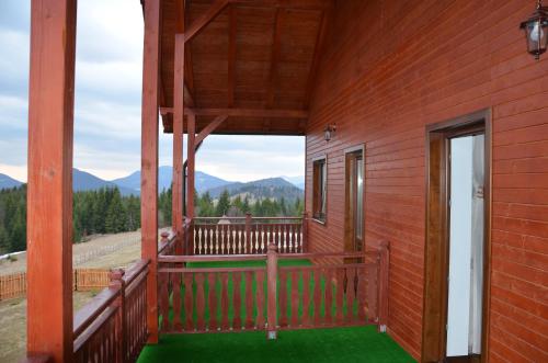 a screened in porch of a red house with a view of the mountains at Pensiunea Zana Muntilor in Piatra Fantanele