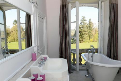 a bathroom with a tub and a large window at Le Château d'Ailly in Parigny