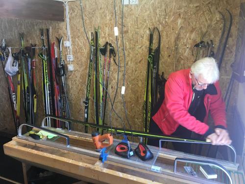 an older woman standing next to a bunch of skis at Ylläksen Yöpuu in Äkäslompolo