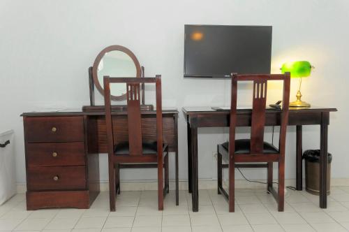 two wooden chairs and a desk with a television at Residence Eburnea in Abidjan