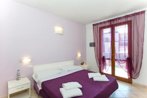 a white bedroom with a purple bed and a window at Residence Riva Blu in Cesenatico