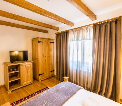 a bedroom with a bed and a tv and a window at Dacii Liberi Resort and Spa in Petrova