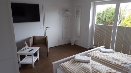 a white room with a bed and a chair and a tv at Hotel Dorfkrug Büsum in Büsum