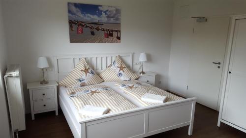 1 cama blanca con almohadas y una foto en la pared en Hotel Dorfkrug Büsum, en Büsum