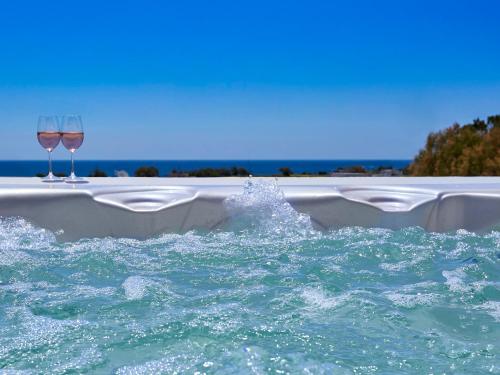 a pool with two glasses of wine in the water at Ambeli Apartments in Perivolos