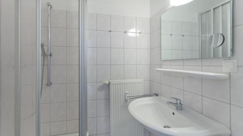 a white bathroom with a sink and a shower at Ferienwohnung in Sellin _ Seepark in Ostseebad Sellin