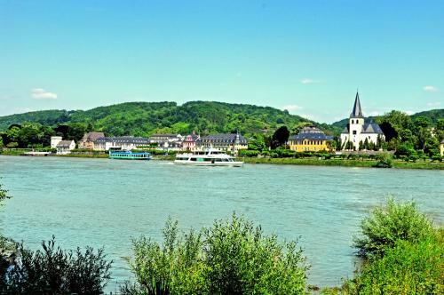 a river with a town and a boat in the water at Gästehaus Korf in Unkel