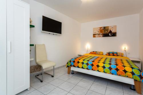 een slaapkamer met een kleurrijk bed en een stoel bij Apartments Danica in Vrbnik