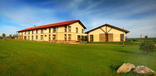 a large building with a red roof on a green field at Wellness Hotel Happy Star in Hnanice