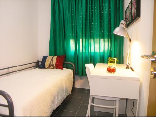 ロス・クリスティアーノスにあるApartment in Cristimar Complexのベッドルーム1室(ベッド1台、デスク、緑のカーテン付)