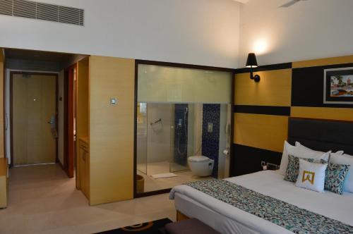a hotel room with a bed and a shower at Welcomhotel by ITC Hotels, Kences Palm Beach, Mamallapuram in Mahabalipuram