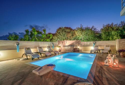 una piscina en un patio trasero con sillas y mesa en Fiorentinos Villa, en Tragaki