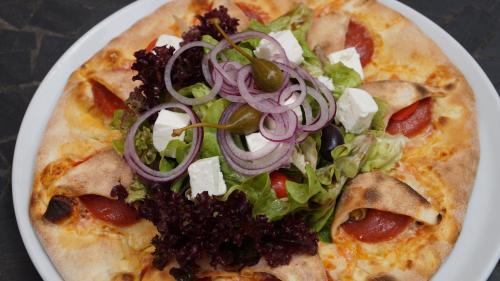a pizza with a salad on a white plate at Hotel YOUHEY am Wolfgangsee in Strobl