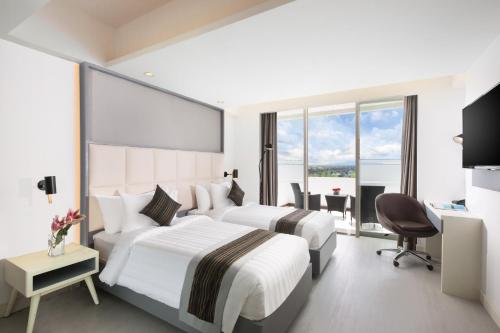 a hotel room with two beds and a desk at INNSiDE by Meliá Yogyakarta in Yogyakarta