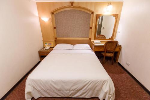 a small room with a bed and a mirror at Champion Hotel in Taipei