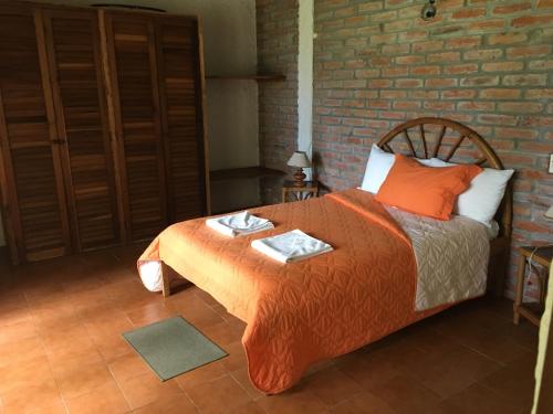 a bedroom with a bed and a brick wall at Hosteria Cumilinche in Same