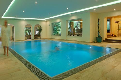 a woman standing in front of a swimming pool in a house at Hotel Waldblick Kniebis in Kniebis