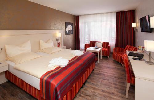 ein Hotelzimmer mit einem großen Bett und Stühlen in der Unterkunft Posthotel Usseln in Willingen