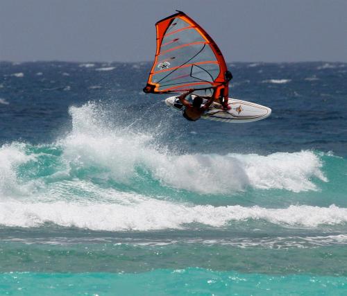 a man riding a windsurfer on a wave in the ocean at Inchcape Seaside Villas in Christ Church