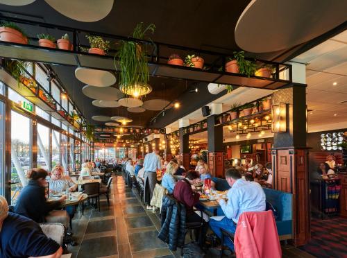 een eetkamer met mensen aan tafel in een restaurant bij Hotel Restaurant Grandcafé 't Voorhuys in Emmeloord