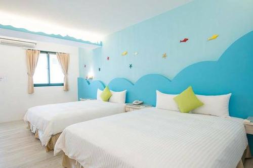 two beds in a bedroom with a blue wall at 看海民宿 in Eluan