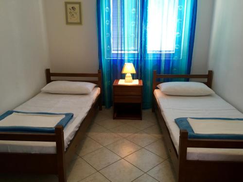 two beds in a room with a lamp on a table at Apartments Sugar in Mandre