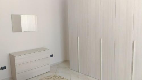 a white bedroom with a cabinet and a mirror at SWEET HOME GIULIA Locazione ad uso turistico in Cimitile