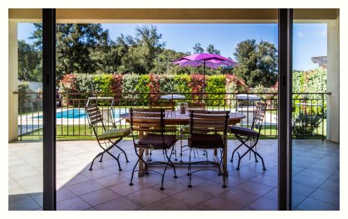 a table and chairs with a purple umbrella on a patio at Villa 4 étoiles Sole di Corsica in Cauro