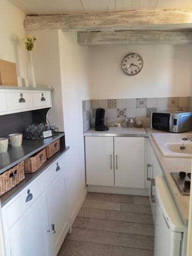 a kitchen with white cabinets and a clock on the wall at Le Clos Des Etoiles in Le Bugue