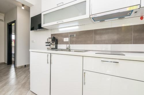 a kitchen with white cabinets and a sink at Boutique Apartments Ad Astra in Bibinje