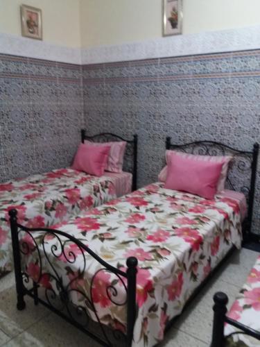 a bedroom with two beds with pink pillows at La Perle in Meknès