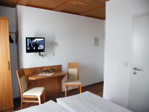 Zimmer mit einem Tisch und Stühlen sowie einem TV an der Wand in der Unterkunft Pension Hofmann-Schmölzer in Rothenburg ob der Tauber
