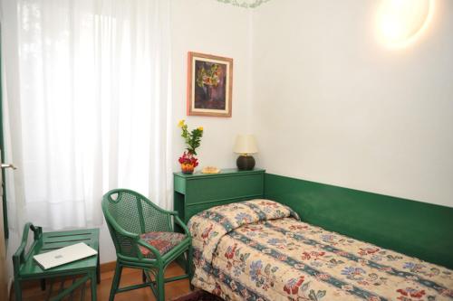a bedroom with a bed and a chair and a table at Hotel Diana in Grado