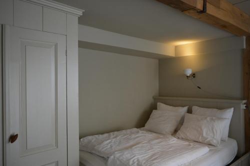 uma cama com lençóis brancos e almofadas num quarto em Waterland Achterhuis em Monnickendam