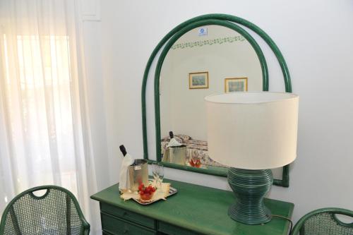 a green dresser with a lamp and a mirror at Hotel Diana in Grado