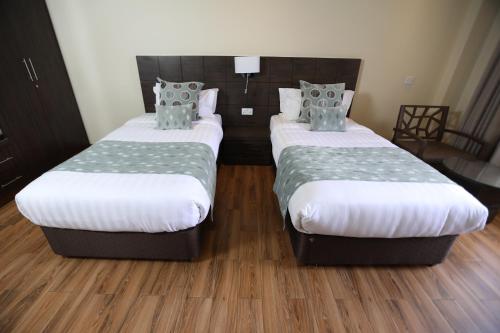 two twin beds in a room with wood floors at Bidwood Suite Hotel in Nairobi