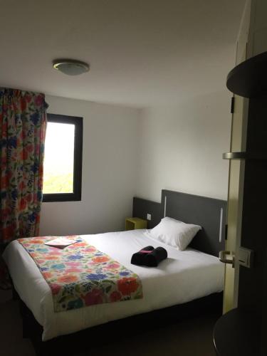 a bedroom with a bed and a window at Kyriad Direct La Rochelle Aytré in Aytré