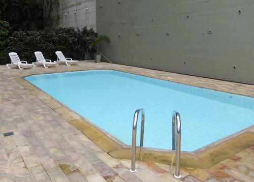 uma grande piscina azul com duas cadeiras brancas em Real Residence Hotel no Rio de Janeiro