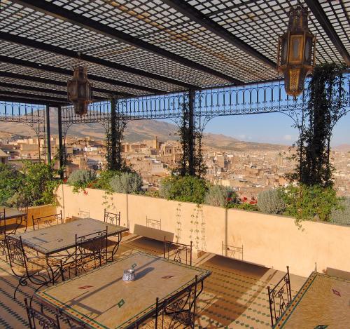 a patio with tables and chairs and a view of a city at Riad Souafine in Fez