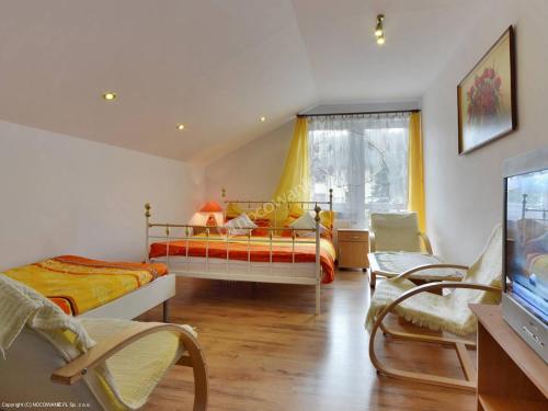 1 dormitorio con 2 camas y TV. en Villa Orzechowski en Wisła