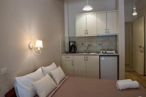 a kitchen with white cabinets and a bed with pillows at Megas Alexandros in Paralia Katerinis